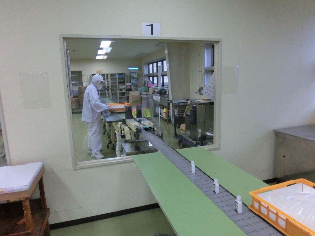 化粧品工場見学-充填が終わったハンドローション達は、ロットの印字をされに、あちら側の部屋に向かいます。 印字はボトルに凸凹があるときれいに印刷されないらしく、一つ目のボトルを通す時はドキドキしましたが、無事にきれいに印刷されました。
